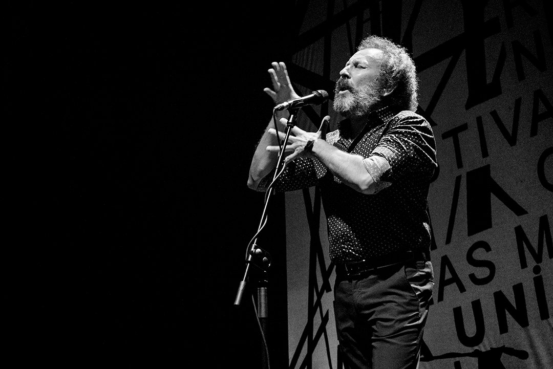 Un cantante gesticula ante un micrófono.
